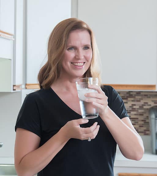 Water Softener Systems | Smiling woman holding a glass of water