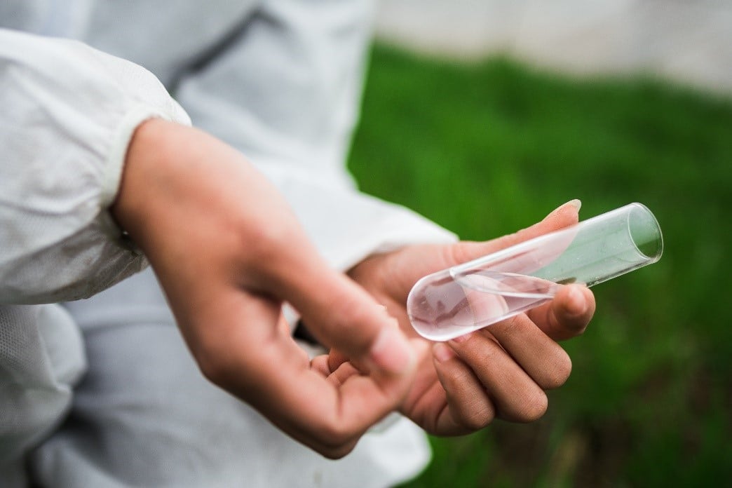 A hand holding a glass test tube with water | Water Testing