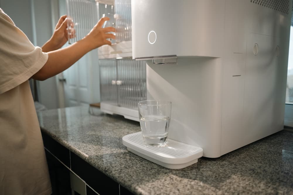 Close-up of a residential water filtration unit on a granite countertop, illustrating the differences between UV water purifier vs RO technology.