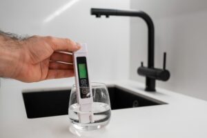 A person using a digital meter to measure the level of TDS in drinking water to ensure home filtration quality.
